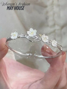 Vòng tay bạc nữ với thiết kế hoa mai trắng tinh xảo, được cầm trên tay