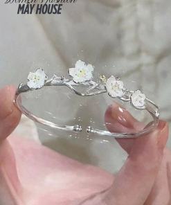 Vòng tay bạc nữ với thiết kế hoa mai trắng tinh xảo, được cầm trên tay